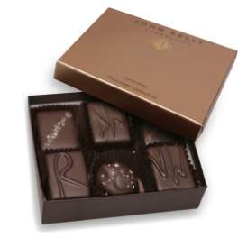 Open brown box of assorted dark chocolates with decorative toppings