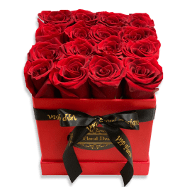 Red roses arranged in a square red box with a black ribbon