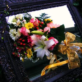 Mixed bouquet with lilies, roses, and daisies tied with a gold ribbon