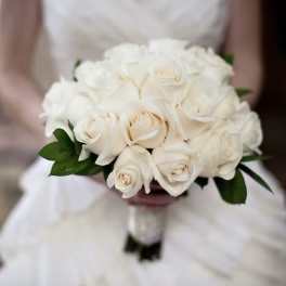 Bride holding a round bouquet of ivory roses.