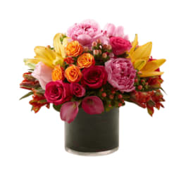 Mixed bouquet of pink, orange, and yellow flowers in a dark vase