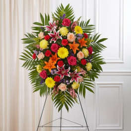 Bright standing spray of mixed pink, yellow, and orange flowers on an easel