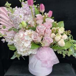 Pink roses and tulips arranged in a white hat box with a pink ribbon