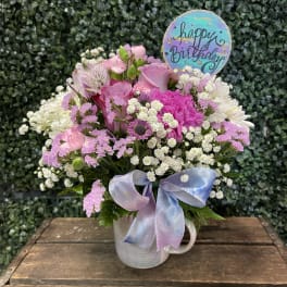 Pink and white mixed bouquet in a mug with a birthday sign and ribbon