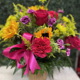 Bright mixed bouquet with roses, sunflowers, and carnations in a vase