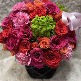 Bouquet of pink, red, and orange roses with a green hydrangea center