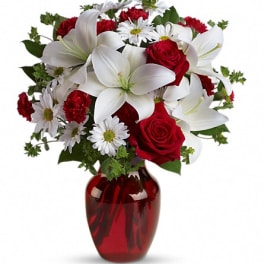 Bouquet of red roses, white lilies, and daisies in a red vase