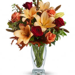 Bouquet of orange lilies and red roses in a clear glass vase