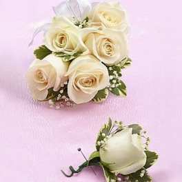 Ivory rose corsage and boutonniere with ribbon on a pink surface