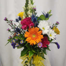 Mixed bouquet with orange gerbera daisies, white daisies, and pink carnations in a glass vase