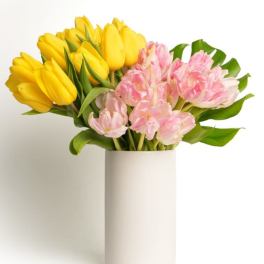 Tall white vase with yellow and pink tulips arranged in two color blocks