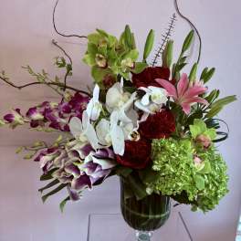 Mixed orchid and lily arrangement in a glass vase