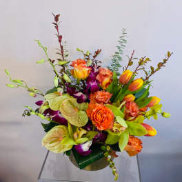 Colorful mixed bouquet with orchids, roses, tulips, and anthuriums in a vase