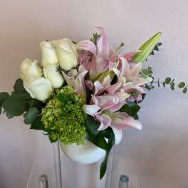 White roses and pink lilies arranged in a white vase