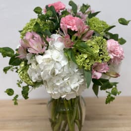 Pink and white flowers arranged in a glass vase