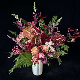Mixed bouquet in a white vase with pink, burgundy, and peach blooms