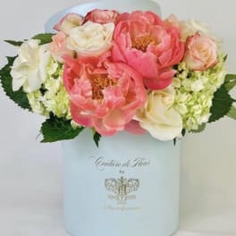 Pink and white flowers arranged in a pale blue hat box