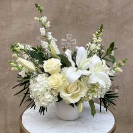 White floral arrangement with roses, lilies, and hydrangeas in a white vase