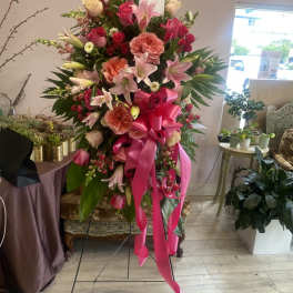Tall pink and peach floral standing arrangement with a bright ribbon