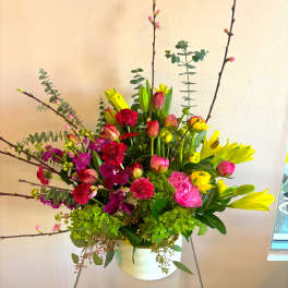 Bright mixed bouquet in a white vase with pink, yellow, and red blooms