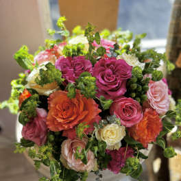 Bouquet of pink, orange, and cream roses with greenery