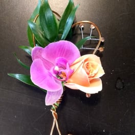 Purple orchid and peach rose boutonniere with green leaves