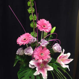 Pink gerberas and lilies arranged in a vase with lavender roses