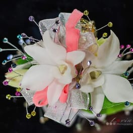 White orchid corsage with pink and silver ribbon and jeweled picks