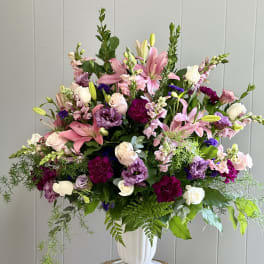 Large mixed bouquet of pink, white, and purple flowers in a white vase