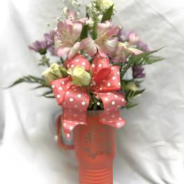 Pink and white flowers in a coral mug with a polka-dot ribbon