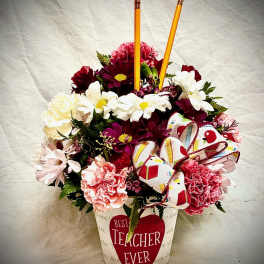 Mixed flower arrangement in a teacher-themed container with pencils and a ribbon bow