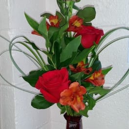 Red roses and orange alstroemeria in a tall vase arrangement