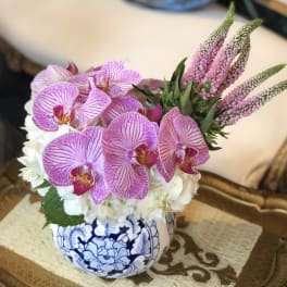 Pink orchids and white hydrangeas in a blue-and-white ceramic bowl