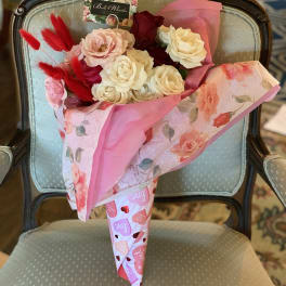 Bouquet of pink, white, and red roses wrapped in pink paper
