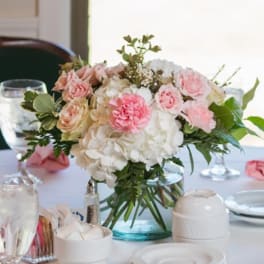 Pink and white floral centerpiece in a glass vase on a table