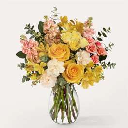 Bouquet of yellow, pink, and white flowers in a clear glass vase