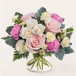 Pink and white roses with carnations in a clear glass vase