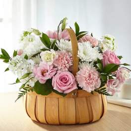 Pink and white flowers arranged in a wooden basket