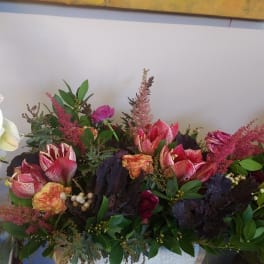 Mixed floral arrangement with pink and red blooms in a white vase