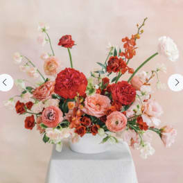 Pink and red floral arrangement in a white bowl vase
