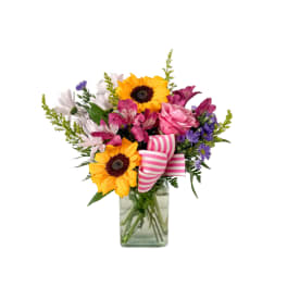 Mixed bouquet with sunflowers, pink roses, and purple flowers in a glass vase