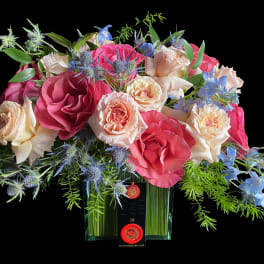 Bouquet of pink and cream roses with blue flowers in a glass vase