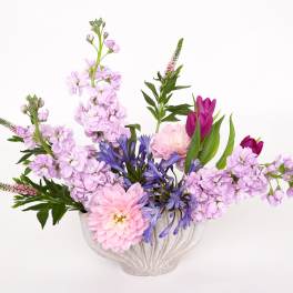 Pink and purple flowers arranged in a white vase