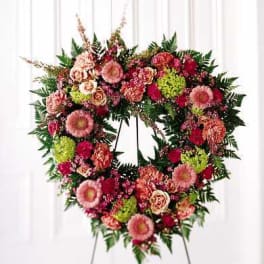 Heart-shaped floral wreath on an easel with pink and red flowers