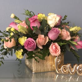 Pink and peach roses in a gold vase with a gold "love" decoration