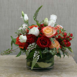 Mixed rose bouquet in a glass vase with white blooms and red berries