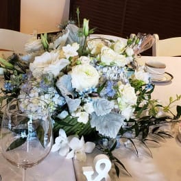 Low centerpiece of white and pale blue flowers on a table