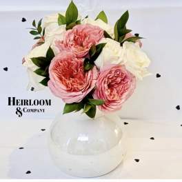Pink and white roses arranged in a clear round vase