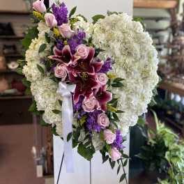 Heart-shaped floral spray with white hydrangeas, pink roses, and purple lilies