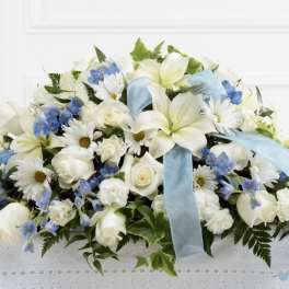 White floral arrangement with blue ribbon and blue accents